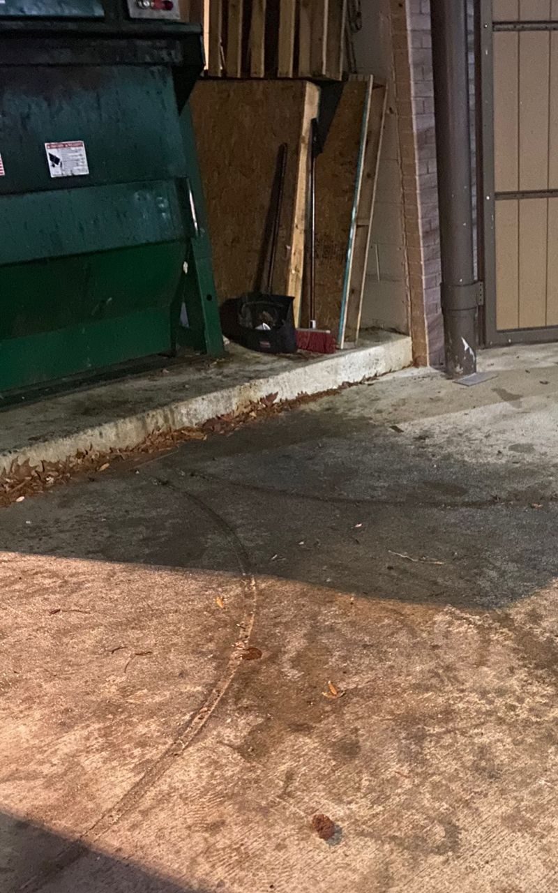 Concrete with orange-brown staining beside a green container, the kind of rust a plain wash often leaves.